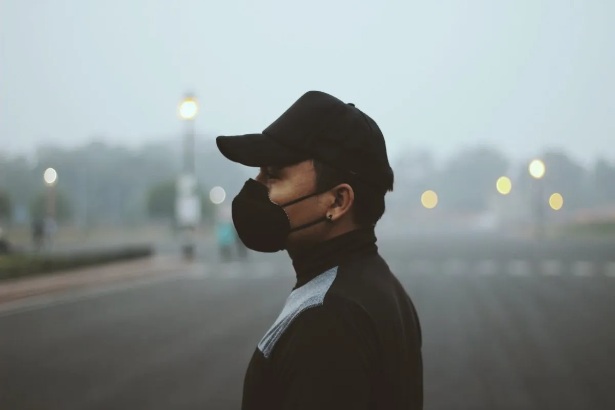 man in black respirator and black cap standing in profile