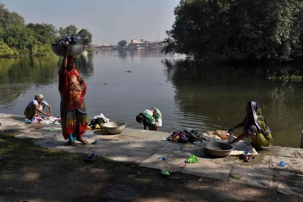 Women washing clothes on the banks of a river near Dakore Temple. Dakor is a city and a Nagarpalika in Kheda district in the state of Gujarat, India. It is prominent for its grand temple of Shree Ranchhodraiji |